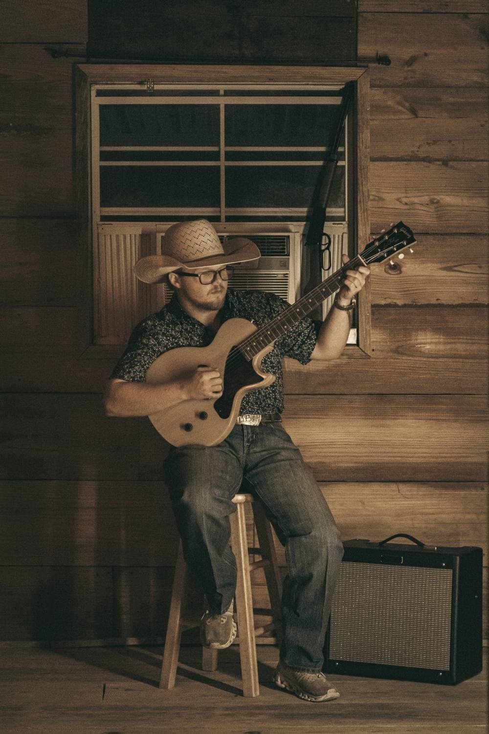 Dalton Grice seated with his guitar in the bunkhouse